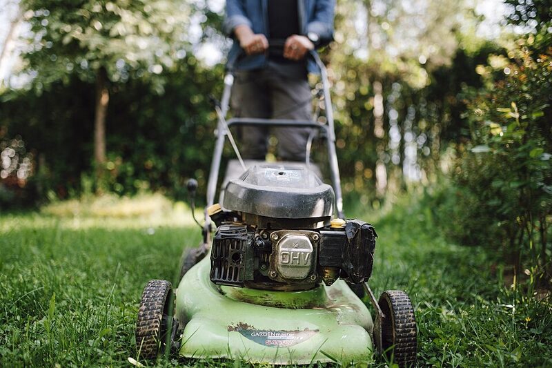 Lawn mower cutting stripes across a green home lawn