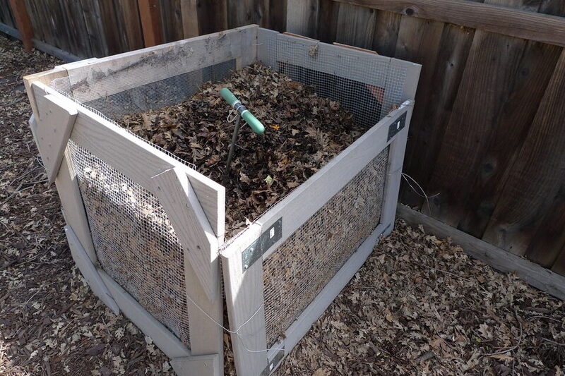 Backyard compost bin full of fallen autumn leaves