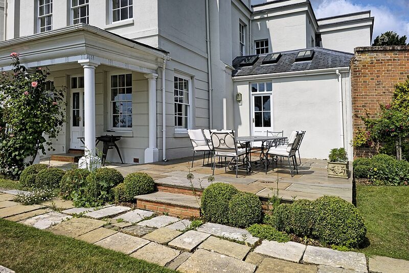 Stone patio with steps and clipped shrubs beside a house