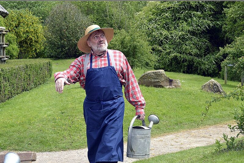 Gardener with a watering can walking through a garden